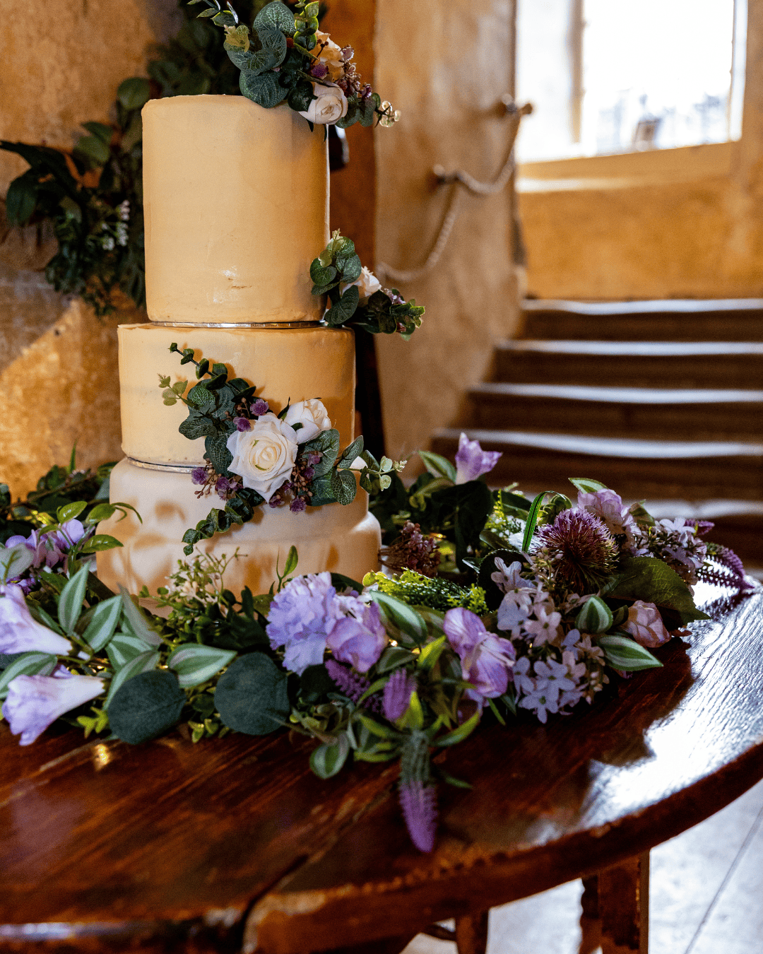 Tiered wedding cake decorated with fresh flowers and greenery