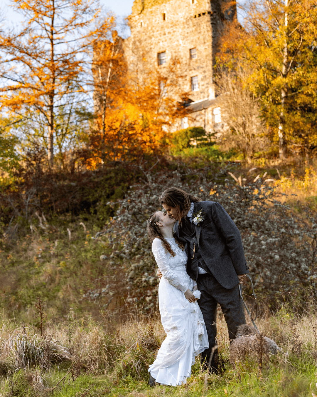 Bride and groom sharing a kiss in front of a Worcestershire manor in autumn