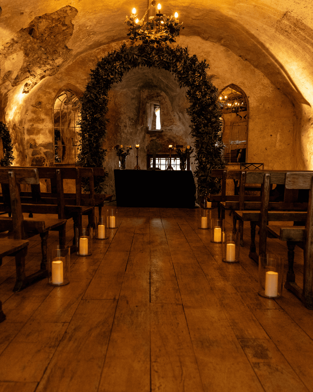 Candlelit ceremony hall with stone vaulted ceiling and flower arrangements